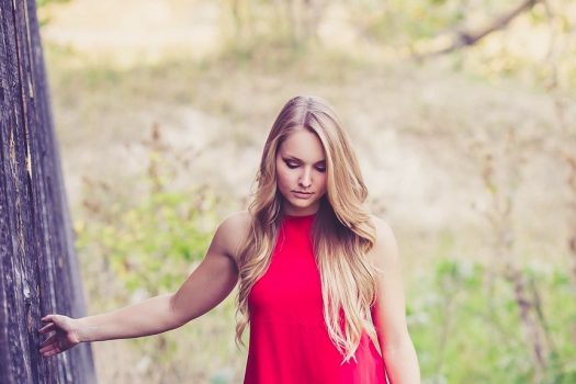 Woman in a red dress and boots walking in grass