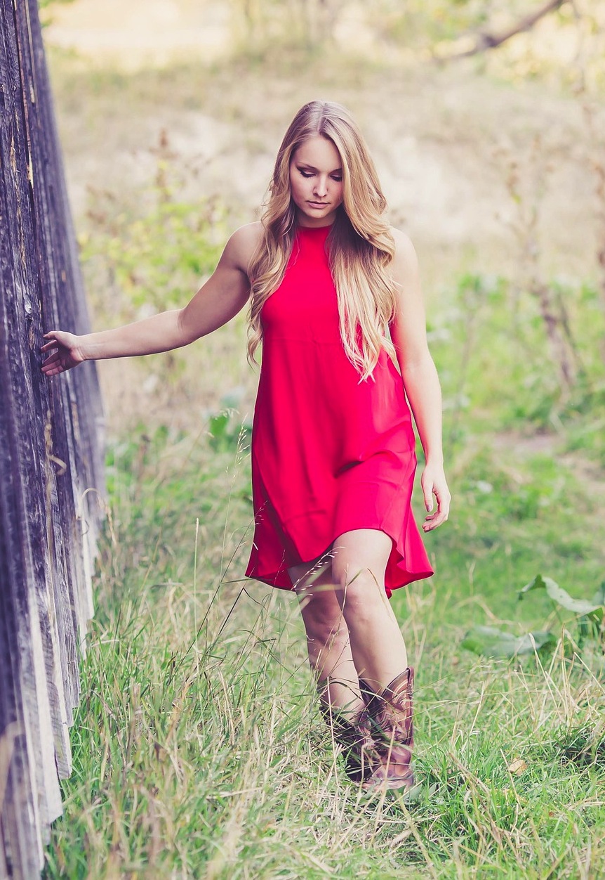 Woman in a red dress and boots walking in grass